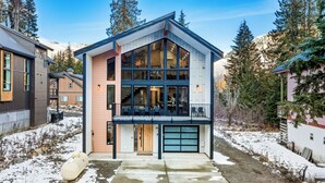 A modern two-story house with large windows, a balcony, and a garage. - LUXE Hyak Retreat w/SAUNA, Hot Tub, Game Room, 6BR (Snoqualmie Pass)