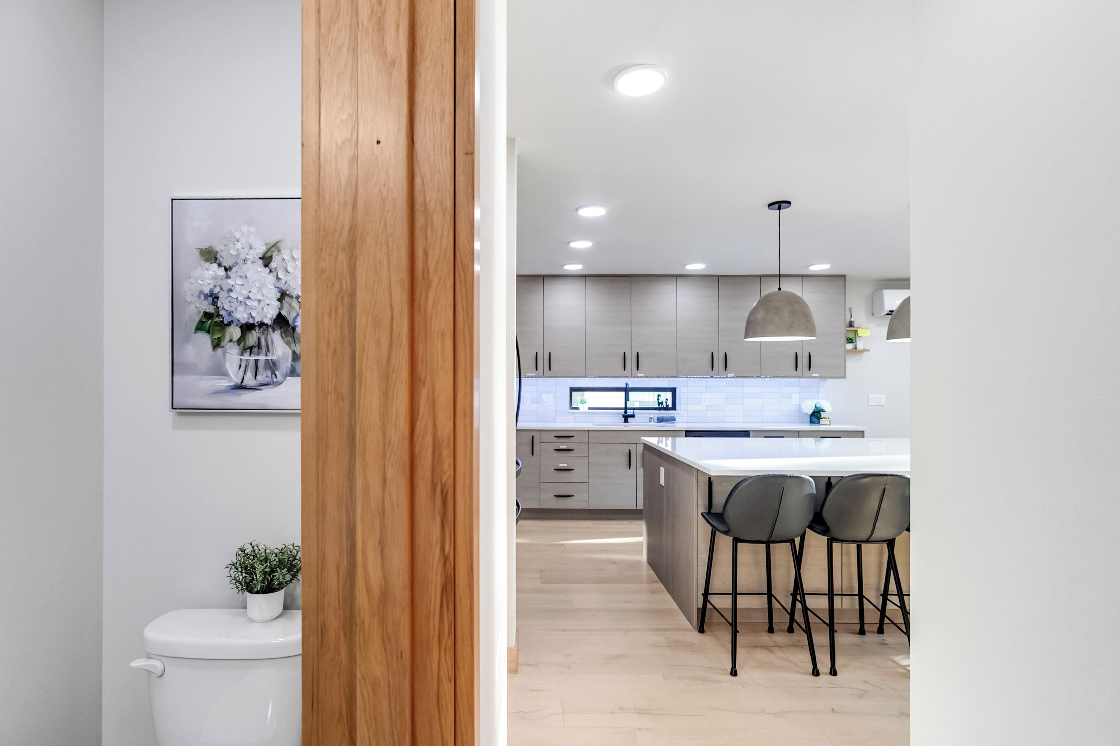 A modern kitchen with a central island, bar stools, and a pendant light.