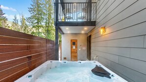 A spa area with a hot tub, wooden deck, and a balcony. - LUXE Hyak Retreat w/SAUNA, Hot Tub, Game Room, 6BR (Snoqualmie Pass)