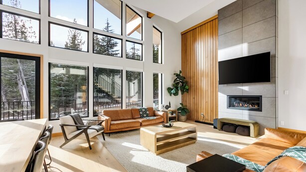 A spacious living room with a large window, a fireplace, and a flat-screen TV. - LUXE Hyak Retreat w/SAUNA, Hot Tub, Game Room, 6BR (Snoqualmie Pass)