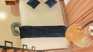 Een bed met kussens, een nachtkastje, een lamp en een bordje met daarop een toilet.