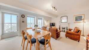 Ein geräumiges Wohnzimmer mit Essbereich, Kamin und großen Fenstern.