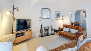 Ein modernes Wohnzimmer mit Flachbildfernseher, Ledersofas, Kamin und Essbereich.