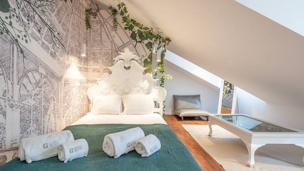 A modern bedroom with a large bed, a green rug, and a glass table. - GuestReady - Autumn Apartment (Bairro Alto)