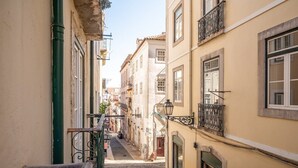 A narrow street with buildings on both sides, a wooden bench, and a metal railing. - GuestReady - Summer Studio (Bairro Alto)