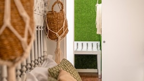 A room with a bed, a macrame wall hanging, a wicker basket, and a macrame wall hanging. - GuestReady - Summer Studio (Bairro Alto)
