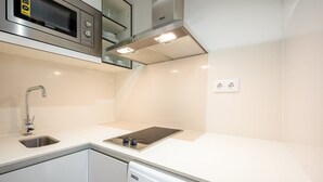 A modern kitchen with a built-in microwave, stove, and dishwasher. - GuestReady - Summer Studio (Bairro Alto)