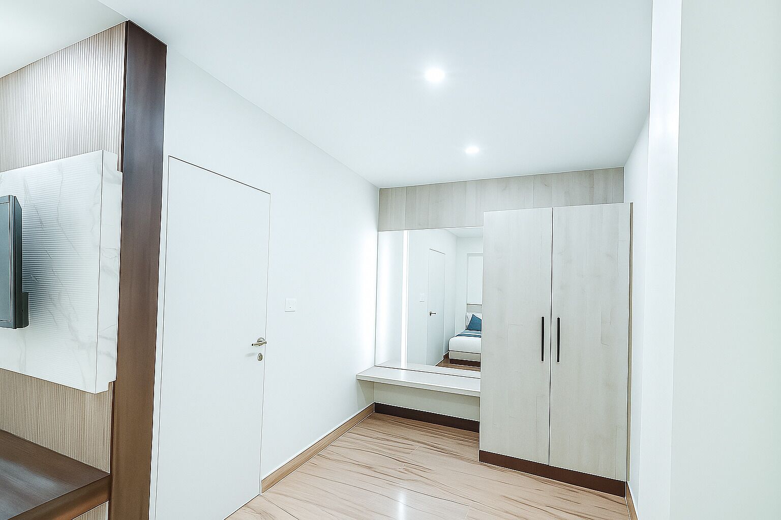 A hallway with a wooden floor, white walls, and a large wardrobe with two doors.