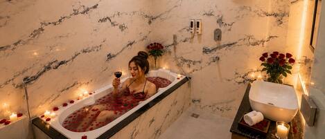 A marble bathroom with a bathtub, shower, and sink.