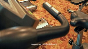 Une salle de sport équipée de tapis de course, d’appareils de musculation et d’un mur recouvert de miroirs.