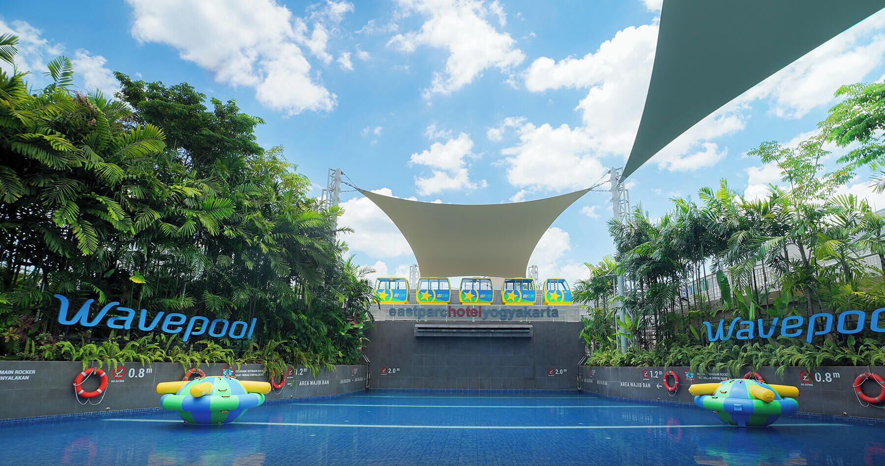 A wave pool with inflatable toys, a canopy, and a view of the Eastparque Hotel Yogyakarta.