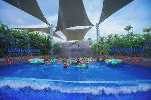 Une piscine à vagues avec plusieurs bouées gonflables et un poste de surveillance pour les sauveteurs.