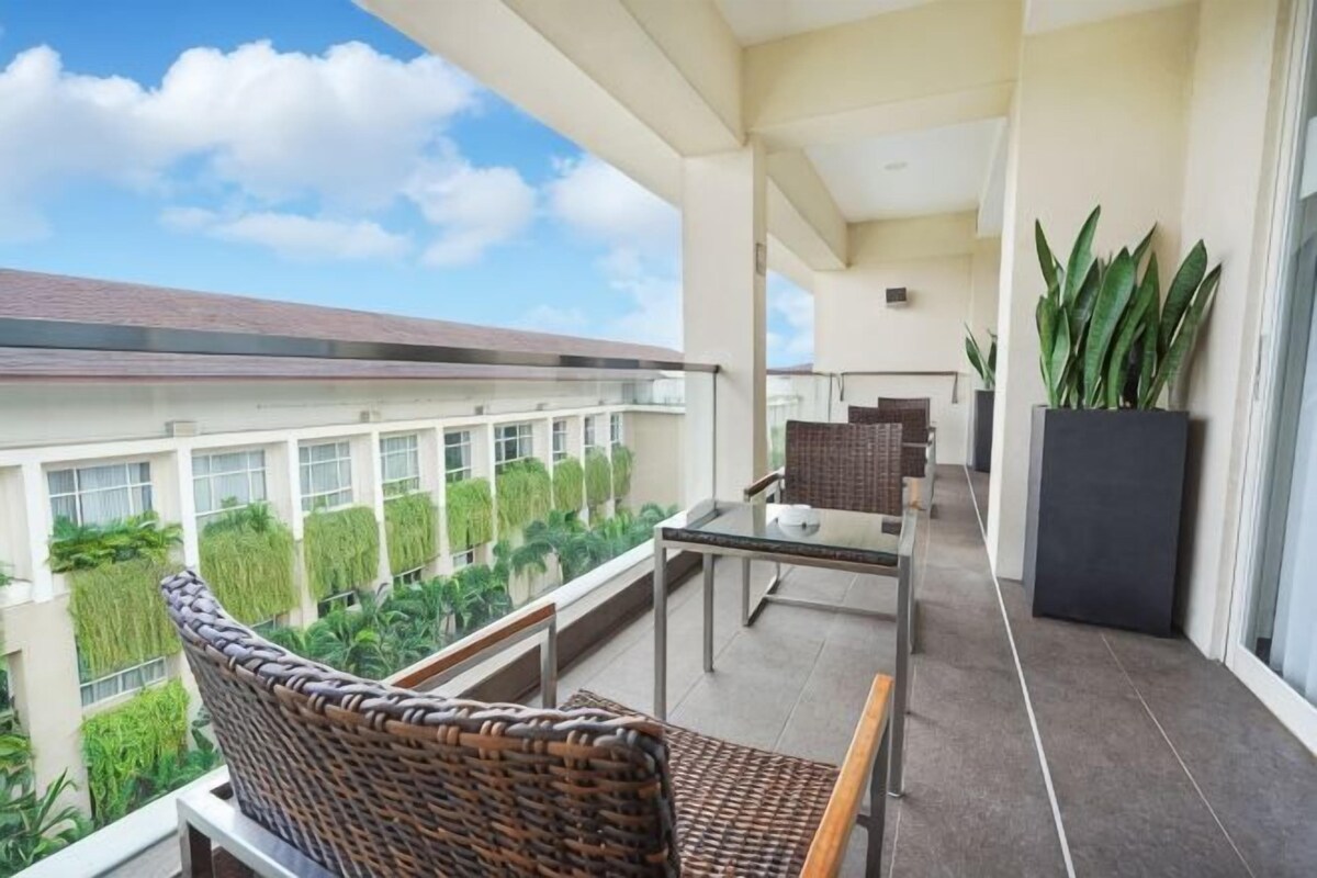 A balcony with wicker furniture, a glass table, and a potted plant.