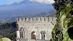 Un edificio histórico de piedra con ventanas de arco y vistas a una montaña nevada.