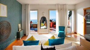 A hotel room with a bed, a view of the sea, a balcony with outdoor seating, and a dining area. - Villa Doride Grande: An elegant and welcoming three-story residence which faces the sun and the sea, with Free WI-FI. (Taormina)