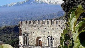A historic stone building with arched windows and a view of a snow-capped mountain. - Villa Doride Grande: An elegant and welcoming three-story residence which faces the sun and the sea, with Free WI-FI. (Taormina)