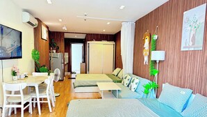 A modern hotel room with a bed, sofa, dining area, and a view of the city. - HOMESTAY 2 GIUONG DOI GAN SAN BAY TAN SON NHAT (Thành phố Hồ Chí Minh)