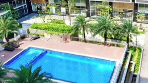 A rectangular pool with a clear blue water surface, surrounded by a paved deck area with lounge chairs and small palm trees. - HOMESTAY 2 GIUONG DOI GAN SAN BAY TAN SON NHAT (Thành phố Hồ Chí Minh)
