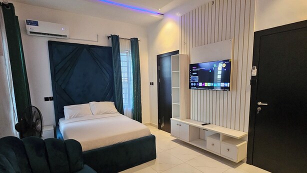 Un dormitorio moderno con una cama, un televisor montado en la pared y una zona de estar con un sofá.
