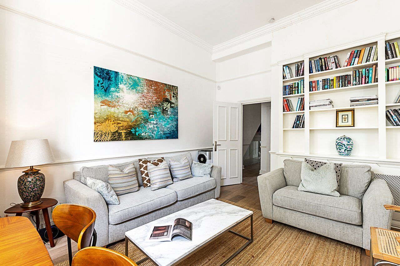 A living room with two grey sofas, a coffee table, a bookshelf, and a large abstract painting on the wall.