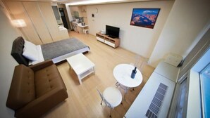 A modern hotel room with a bed, a sofa, a small table, a TV, and a window. - Incheon Airport Prime Guesthouse (Incheon)