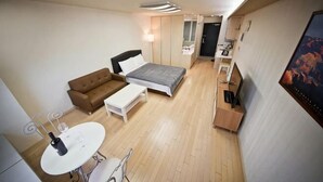 A compact hotel room with a bed, a sofa, a small table, and a TV. - Incheon Airport Prime Guesthouse (Incheon)