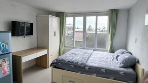 Une chambre à coucher avec un lit, un bureau, une armoire et un téléviseur.