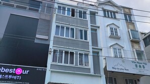 Un immeuble à plusieurs étages abritant divers commerces au rez-de-chaussée, notamment un restaurant et un espace de restauration rapide.