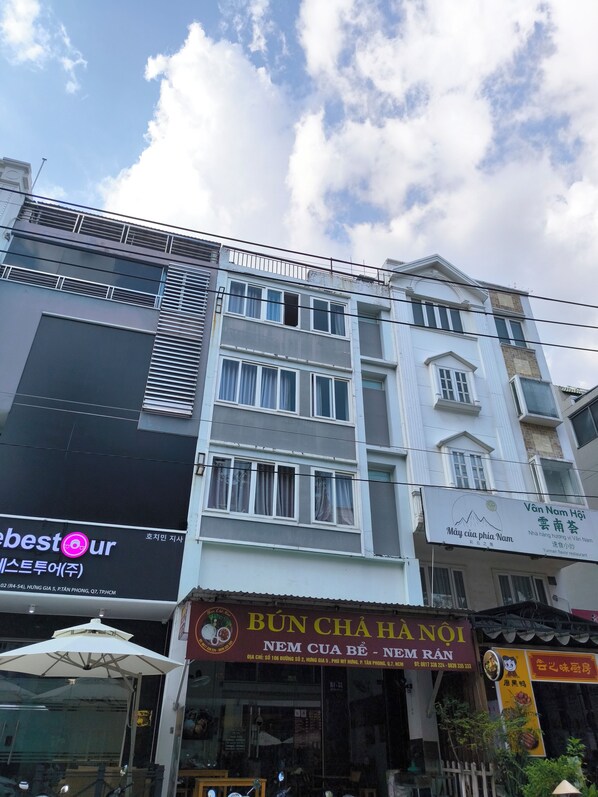 Un immeuble à plusieurs étages abritant divers commerces au rez-de-chaussée, notamment un restaurant et un espace de restauration rapide.