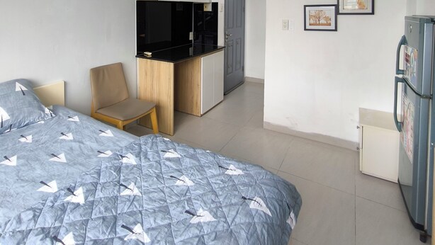 Une chambre d’hôtel de taille réduite, comprenant un lit, une petite kitchenette, une chaise et un réfrigérateur.