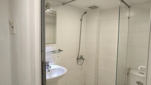 Une petite salle de bain moderne avec une douche à parois de verre, un lavabo blanc et des toilettes.