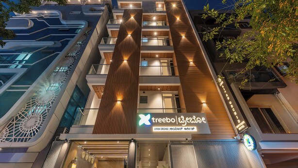 A modern hotel with a prominent vertical tower, multiple balconies, and a sign indicating it is the Liyan Orchid. - Treebo Liyan Orchid, Hsr Layout (Bengaluru)