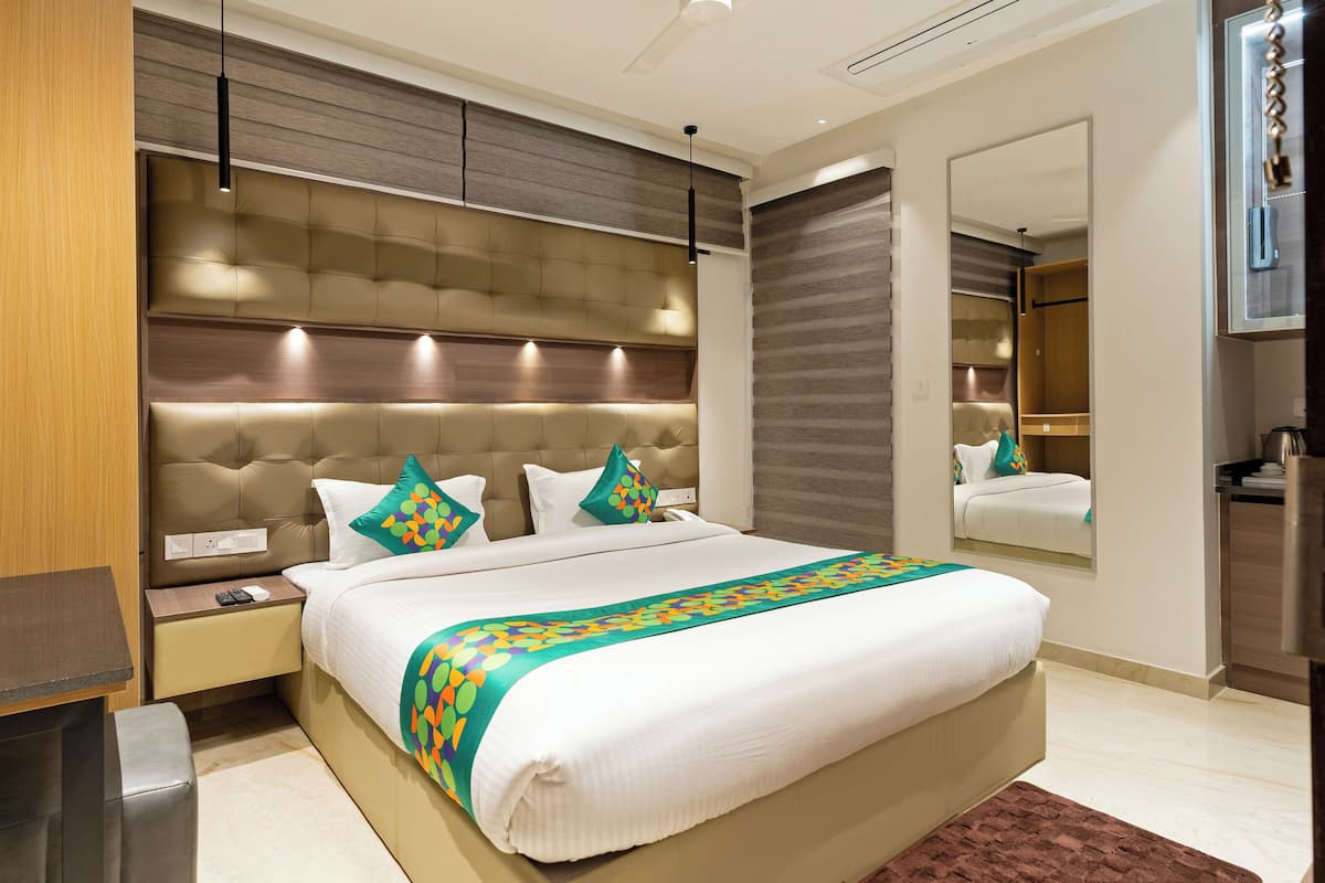 Een moderne hotelkamer met een groot bed, een nachtkastje, een spiegel en een potplant.