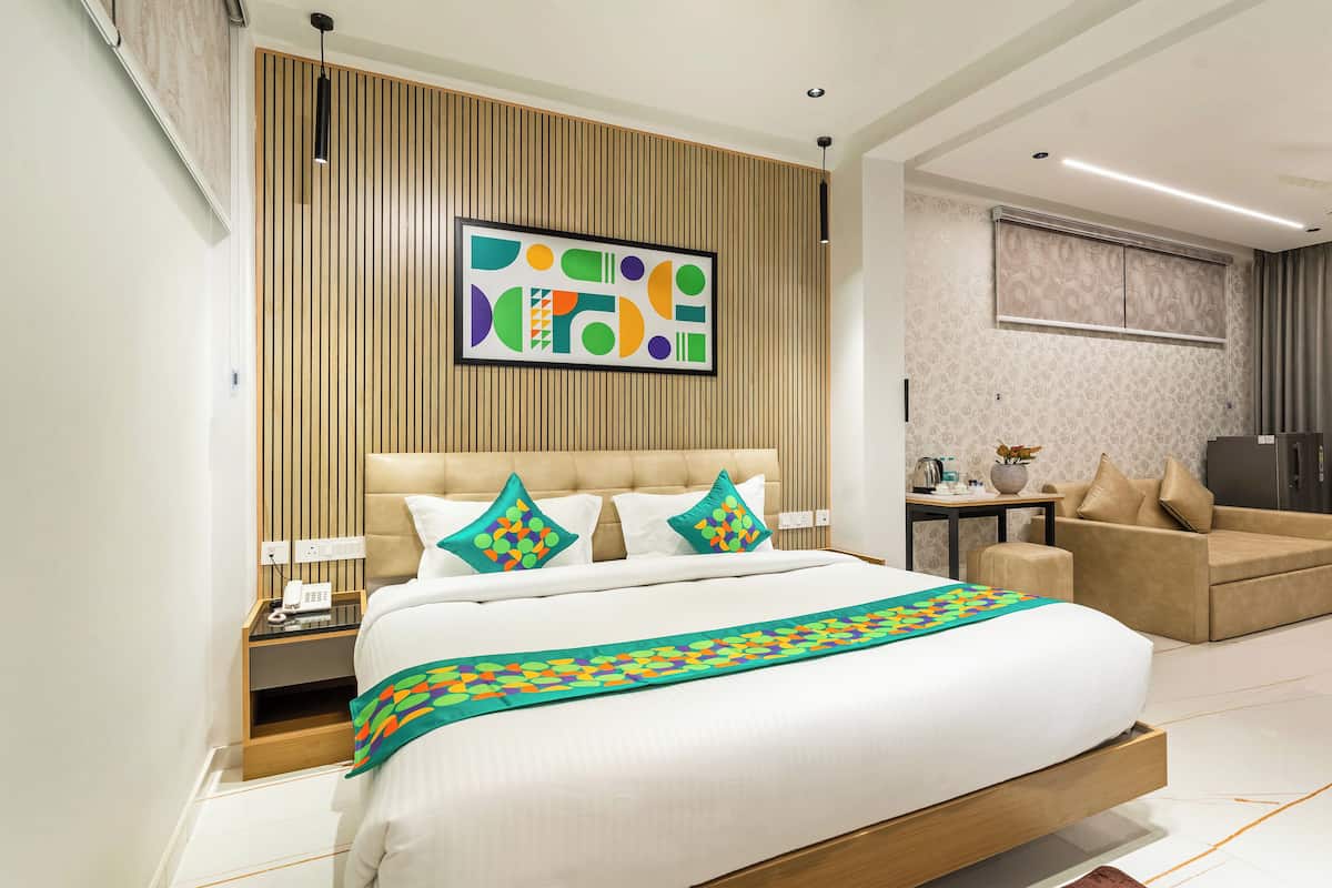 Een moderne hotelkamer met een groot bed, een sofa, een klein tafeltje en een plafondventilator.