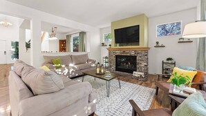 Un salon moderne avec une cheminée, un canapé, une table basse et un téléviseur fixé au-dessus de la cheminée.