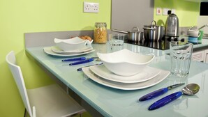 Eine Küche mit grüner Wand, einem weißen Stuhl und einem Tisch, der mit Tellern, Schüsseln und Besteck gedeckt ist.