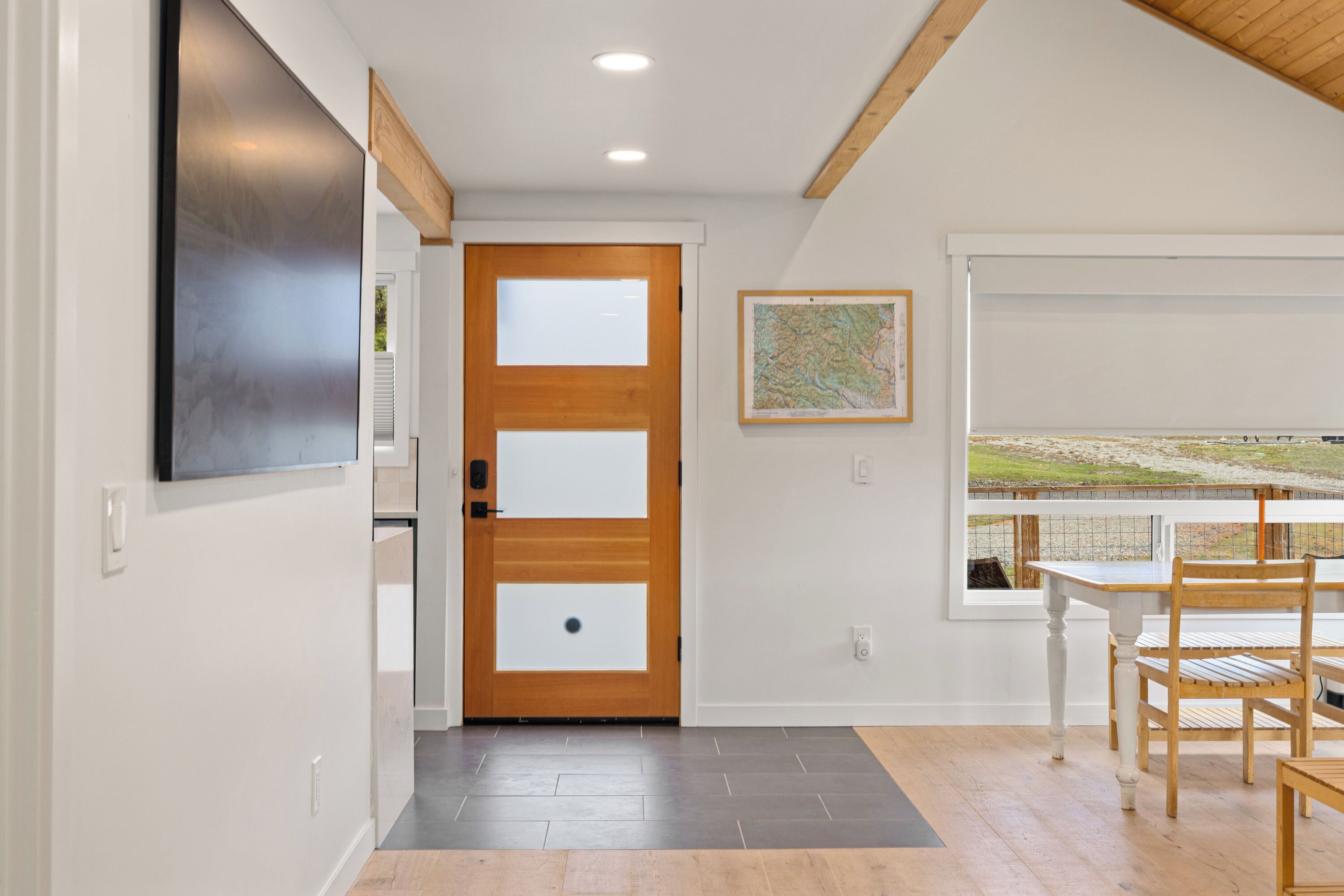 Een modern interieur met een houten deur, een kaart aan de muur en een eethoek met uitzicht.