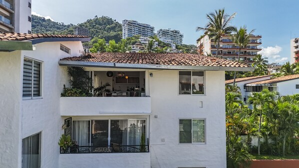 A two-story building with a tiled roof, balconies, and a view of surrounding buildings and greenery. - Condo for rent in Old Town #3519 2BD Condo for rent in Old Town, Puerto vallarta (Puerto Vallarta)