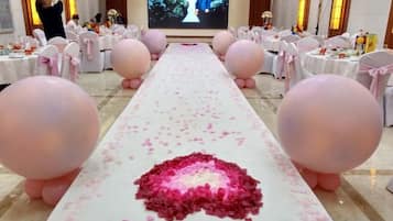 A long table with a white tablecloth, pink balloons, and rose petals arranged in the center.