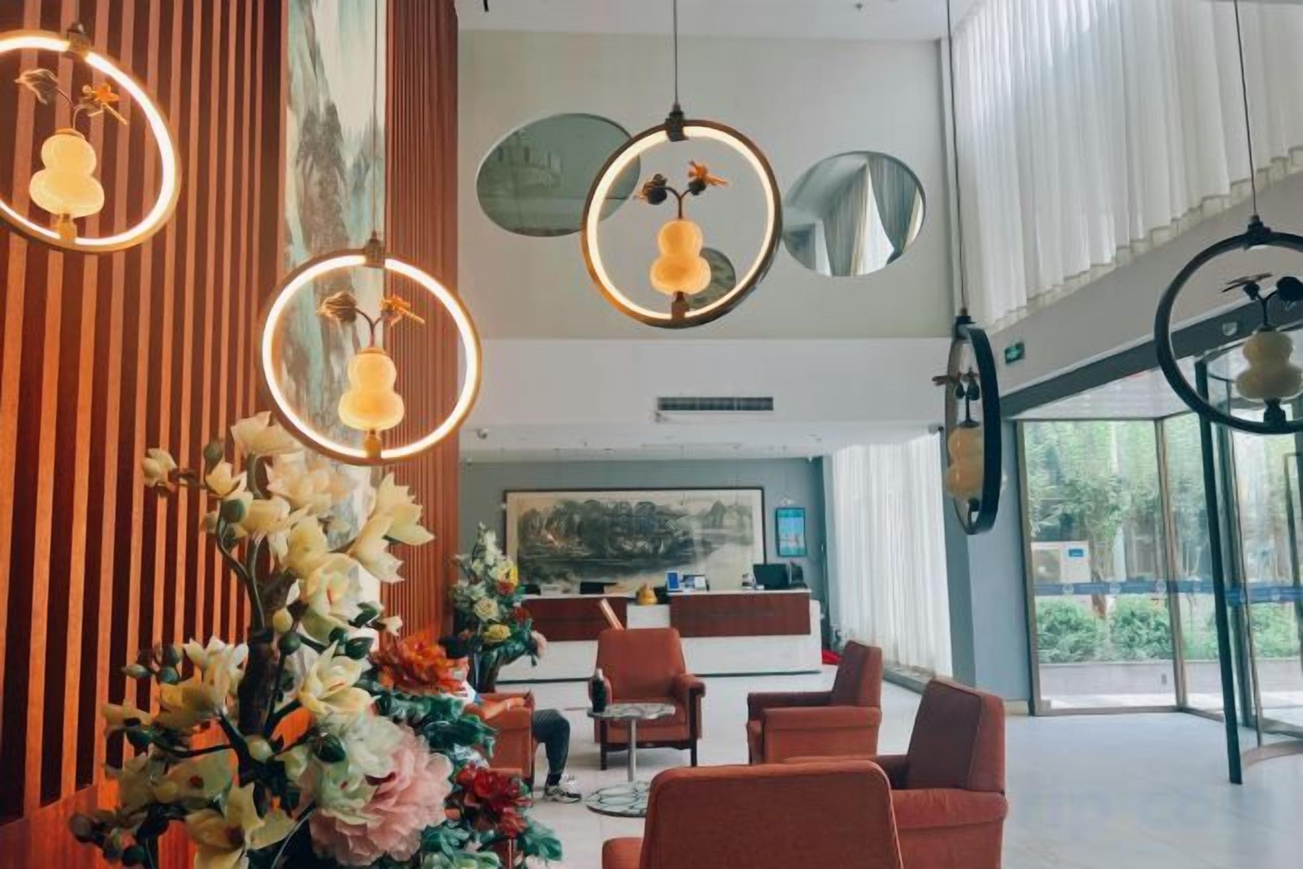 A modern hotel lobby with a reception desk, seating area, and large windows.