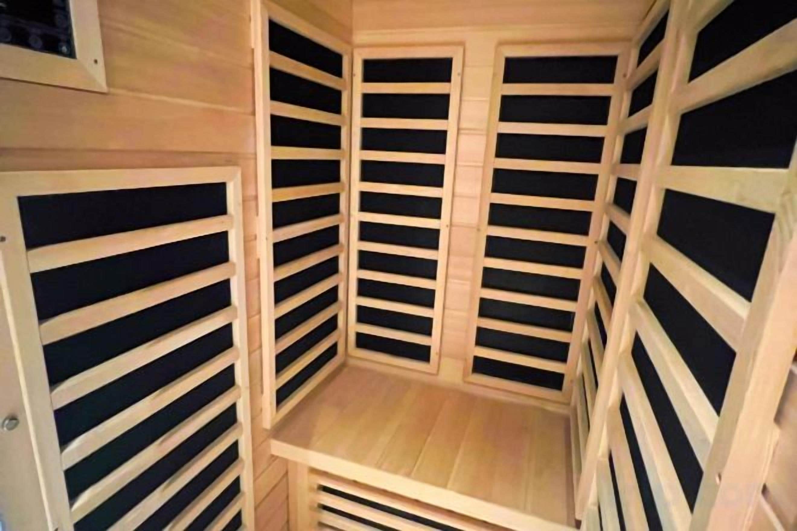 A room with a slatted wooden ceiling and walls, a central wooden platform, and a door.