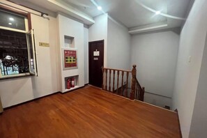 Ein Flur mit Holzboden, einer Treppe und einem Brandschutzplakat an der Wand.