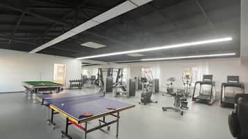 A gym with exercise equipment, a ping pong table, and a treadmill.