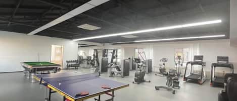 A gym with exercise equipment, a ping pong table, and a treadmill.
