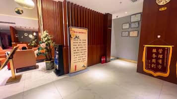 A hotel lobby with a reception desk, a Christmas tree, and a wall with framed certificates.