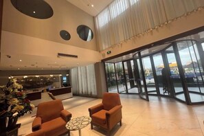 Un hall d’hôtel comprenant un comptoir d’accueil, un espace salon et de grandes fenêtres.