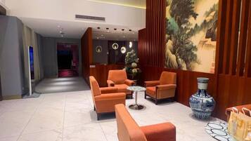 Eine Lobby mit Sitzgelegenheiten, einer Vase und einem Wandgemälde.