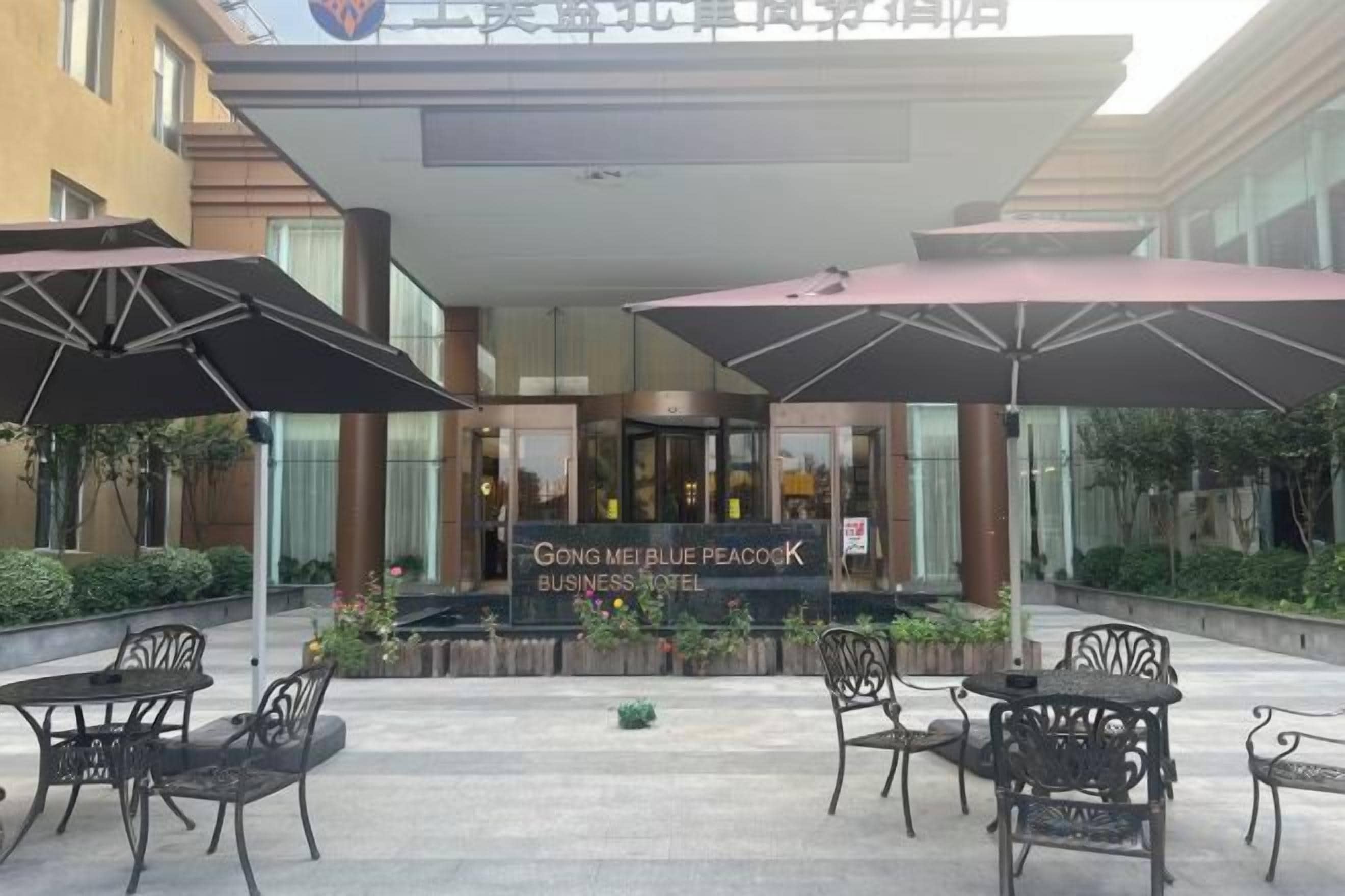A business hotel entrance with outdoor seating and umbrellas.