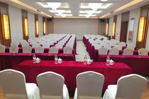Une salle de conférence avec des rangées de tables et de chaises, équipée de bouteilles d’eau et de plaques nominatives.