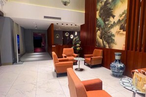 A lobby with orange seating, a vase, and a painting. - Gong Mei Blue Peacock Business Hotel (Beijing Xisanqi) (Beijing)